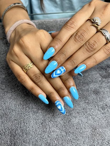 A bright and trendy light blue set with accent nails featuring a layered heart design.