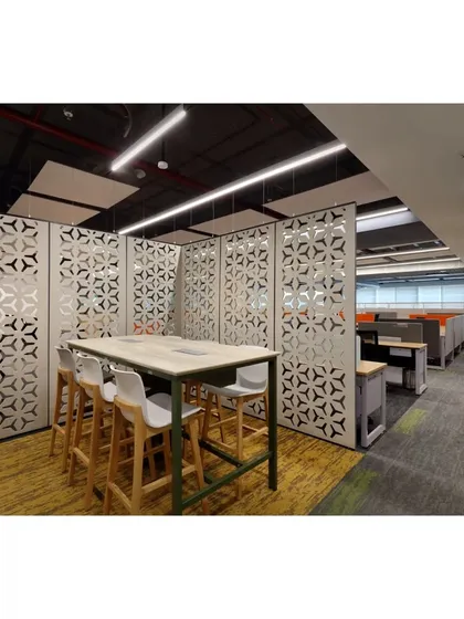 A high-top collaboration table enclosed by patterned privacy screens. This setup creates a semi-private meeting point within the open office, balancing the need for teamwork and concentration.