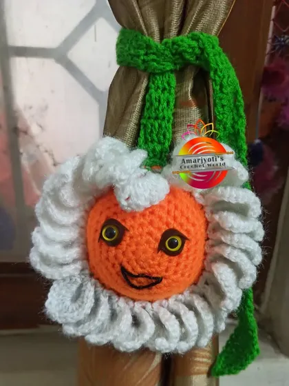 This is a fun, character-inspired curtain tie-back. It features a smiling orange face surrounded by fluffy white petals, bringing a cartoonish charm to your decor.