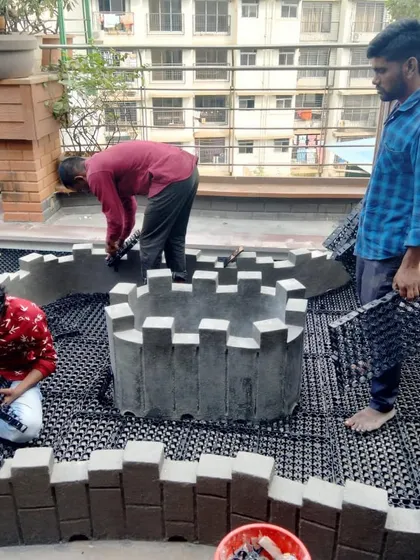 Our team constructing circular planter beds on a terrace. This behind-the-scenes look shows the structural work that goes into our custom garden installations before any soil or plants are added.