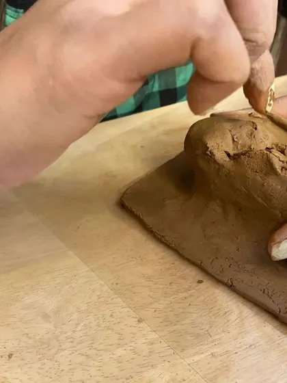 A participant using their fingers to refine the form of their clay sculpture. Hand-building is a fundamental pottery skill that allows for immense creativity and control over the final piece.