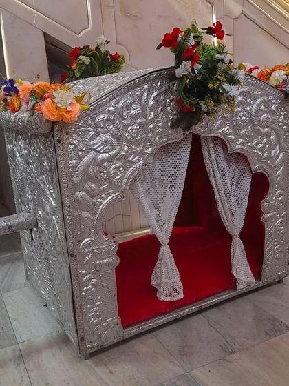 For a more classic and enclosed option, I offer this silver-plated palki. It features intricate carvings and curtains for privacy, giving it a very traditional and royal feel.