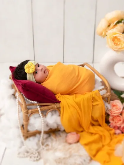 A full view of our yellow-themed setup, with the newborn resting in a miniature cane bed surrounded by yellow roses. This image highlights the thoughtful composition and styling that goes into every one of our themed shoots.