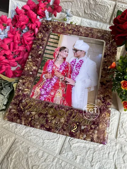 This 9x12 inch rectangular resin frame preserves wedding garlands around a central photo. The couple's names and date are written in elegant golden script.