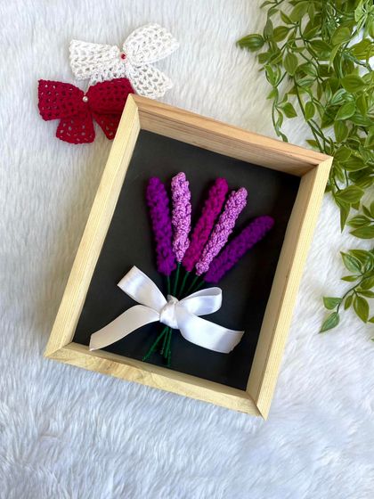Another view of the framed lavender bouquet, this time against a dark background which makes the purple colors pop. The solid wooden frame and glass cover protect the delicate crochet work.