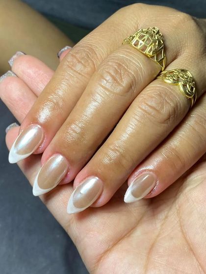 A pearlescent French tip on almond nails. The chrome finish on the tip gives this classic look a modern, trendy update.