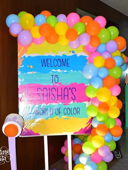 The welcome sign for 'Saisha's World of Color', framed by a bright balloon garland, setting the artistic tone right from the entrance.