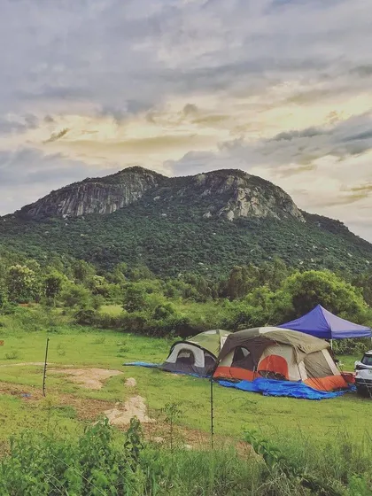 Car camping at the base of a large rock formation. This setup shows how you can have a comfortable basecamp with a vehicle, perfect for exploring the surrounding hills and enjoying the wide-open green spaces.