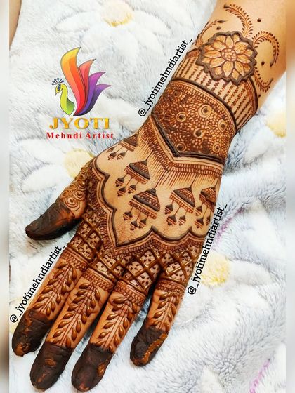 A detailed back-hand design for a bride or engagement. The pattern features traditional hanging jhumkas and leafy vines on the fingers, creating an elegant look.