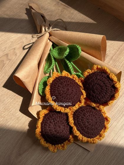 Our four-stem crochet sunflower bouquet laid flat, showing the simple and elegant wrapping. It's a perfect, ready-to-gift bundle of sunshine.