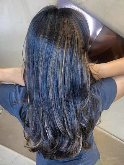 Subtle and cool-toned blonde highlights on dark hair. The hair is styled with a gentle wave to show how the light catches the different colors.