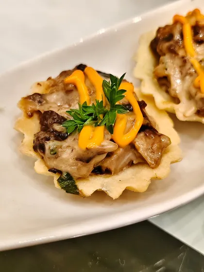 A crisp pastry shell holds a creamy mushroom and cheese medley, finished with a drizzle of zingy sauce. This is the ultimate one-bite wonder.