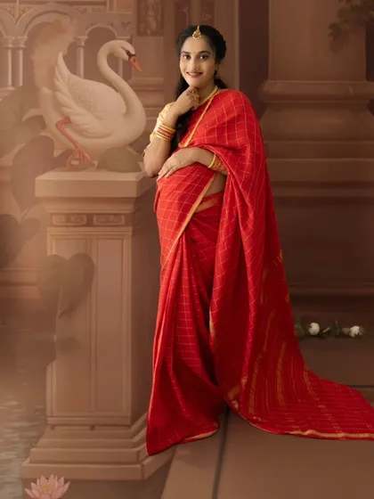 A beautiful solo portrait of a mom-to-be in a red saree, posing elegantly next to a painted swan statue.
