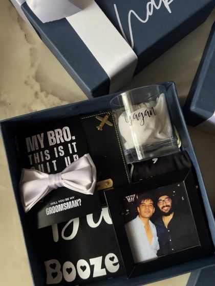 Inside the groomsmen proposal box, you'll find a mix of fun and practical items. This one features a personalized glass, a bow tie proposal card, a framed photo, and a custom passport cover.