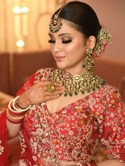 A closer look at the intricate details of this Kundan bridal set. The combination of gold, pearls, and green stones is a classic choice for Indian brides.