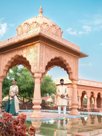 A formal portrait of the couple at the royal venue. They are standing apart but connected by the grand setting, creating a powerful and stately image that emphasizes the scale of the location.
