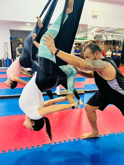An instructor provides a gentle adjustment to help a student find more depth and alignment in an inverted aerial pose. This personal attention is key to a safe and effective practice.