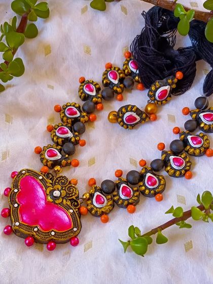 A beautiful heart-shaped pendant necklace in pink and orange. The chain features smaller, matching beads, making it a very romantic and coordinated set.