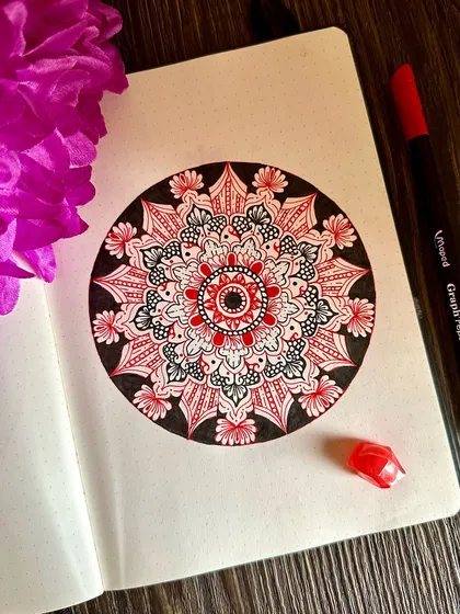 A pop of red brings a different energy to this otherwise black and white piece. The selective use of color draws the eye to the center, highlighting the core of the intricate mandala design.