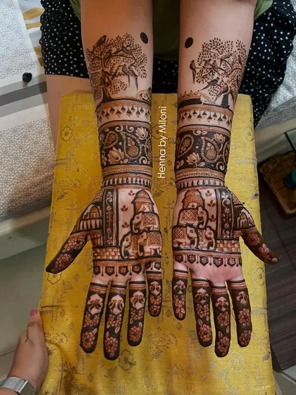 A unique bridal mehendi featuring a story of nature. The design includes a banyan tree, birds, and elephants, creating a beautiful narrative on the bride's arms.