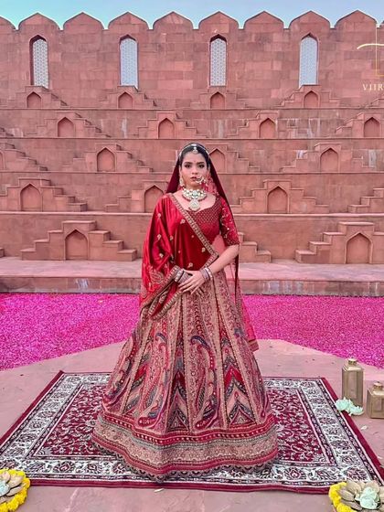 A full-length view of the classic red bridal lehenga, set against a dramatic backdrop that highlights its grandeur.