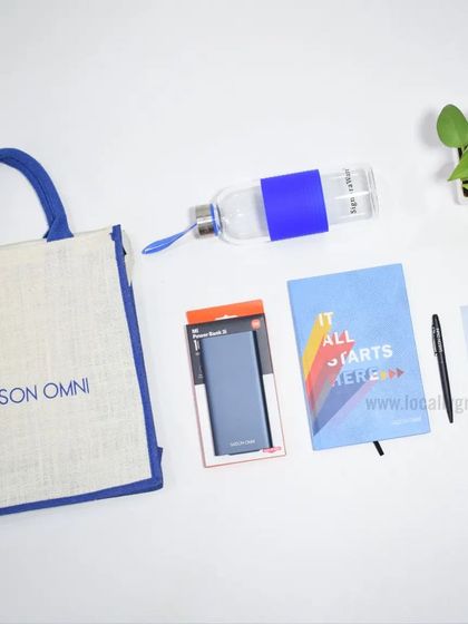 This onboarding kit for Saison Omni combines practicality with eco-consciousness. It includes a branded jute bag, a glass water bottle, a power bank, and a notebook that says "It All Starts Here."