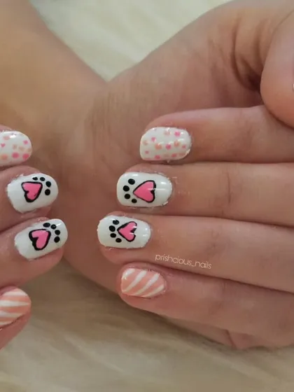 A full view of the cat paw manicure, complete with polka dots and stripes for an extra playful touch.