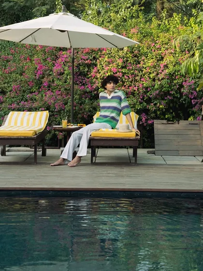 A wide shot of a guest relaxing by the pool, capturing the full scale of the deck and the lush surroundings.