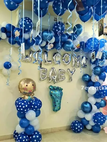 A welcome baby decoration in blue and white with polka-dotted balloons and a baby-shaped foil balloon column.
