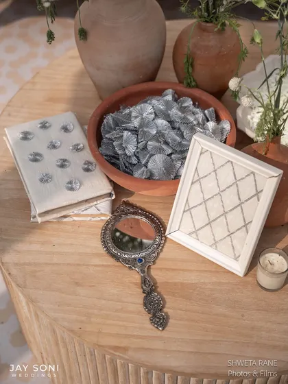 A collection of curated objects for the ivory wedding, including a traditional silver hand-mirror and other trinkets, adding a personal and vintage touch.