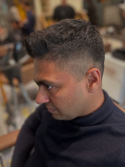 A side profile of a clean, sharp fade. The transition from the skin to the longer hair on top is seamless, creating a very polished and professional men's haircut.
