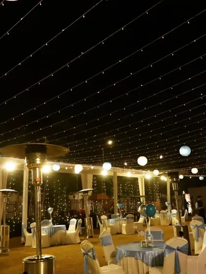 Creating a dreamy ambiance with a canopy of fairy lights for an outdoor evening event. This lighting setup, combined with elegant table arrangements and patio heaters, ensures a comfortable and magical atmosphere for guests.