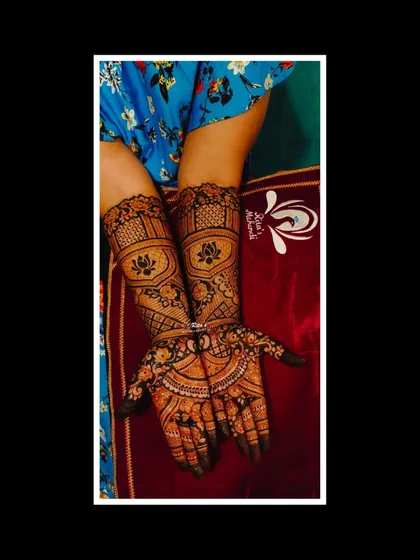 An elegant engagement mehendi with a large, symmetrical mandala design on the palms, surrounded by detailed patterns on the fingers and arms.