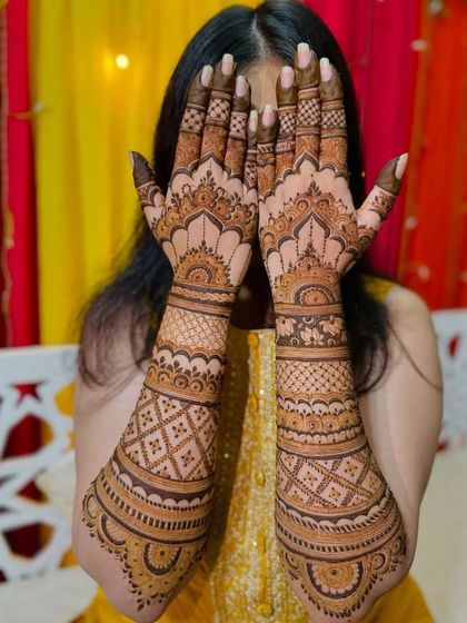 A bride playfully peeking through her beautifully adorned hands. This design features classic architectural tops and intricate jaali work.