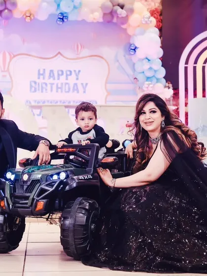 The birthday boy with his parents and his new toy jeep at his party.