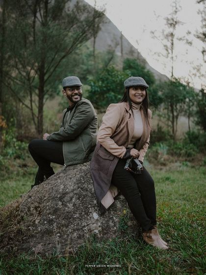 Ananthu and Sarga enjoying a moment together on a rock. The natural, earthy tones of their outfits blend perfectly with the rustic landscape.