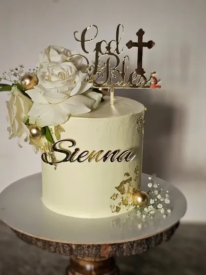An elegant baptism cake for Sienna, in white and gold with fresh white roses and a "God Bless" topper.