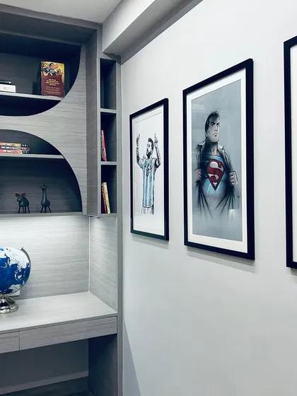 This corner study nook within a teenager's room is both stylish and functional. The curved shelving adds a soft, unique design element, while the sports-themed posters reflect the occupant's personality.