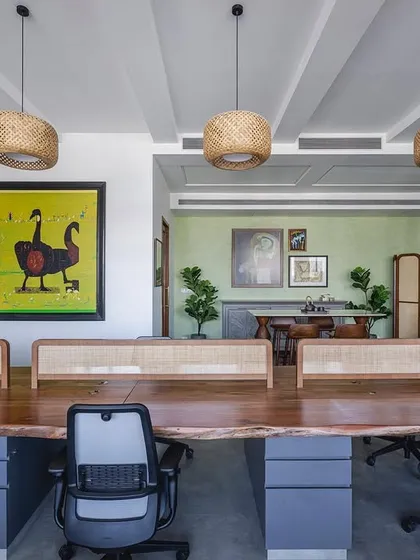 The 'Sepalika' office features a large, live-edge wood workstation with cane partitions. This setup breaks away from typical office cubicles to foster a more cozy and interactive atmosphere.