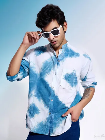 A classic portrait-style shot for a menswear lookbook. The model adjusts his sunglasses, adding a cool, casual vibe that complements the hand-dyed shirt.