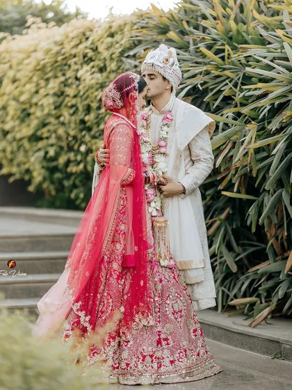 A romantic kiss shared by the couple on the steps, surrounded by lush greenery, a beautiful and intimate wedding day portrait.