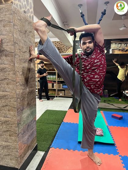 Another student working on the standing split, showing how the belt and wall provide the necessary support to hold this challenging posture.