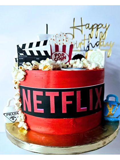 Perfect for a movie marathon birthday, this Netflix-themed cake has it all. It features the iconic red and black logo, edible popcorn, a movie clapperboard, and even tiny designer bags for a touch of glam.