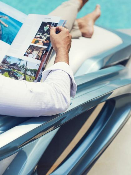 A detail shot focusing on the ergonomic design and luxurious feel of the chair, perfect for relaxing with a magazine by the pool.