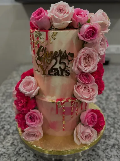 A two-tiered masterpiece for a 25th wedding anniversary, blending rich Belgian chocolate and refreshing Mango Vanilla flavors. The design features a cascade of fresh pink roses and delicate gold leaf for a touch of luxury.