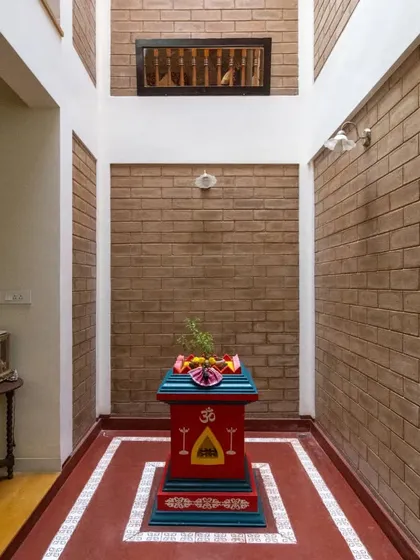 The central courtyard, a core feature of the home, housing a traditional Tulasi Katte against a backdrop of exposed brick, connecting the home to both nature and spirituality.