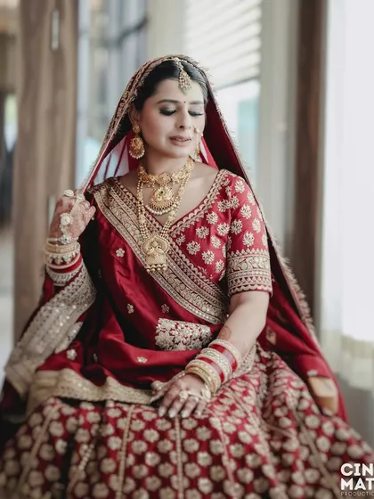 A quiet, seated portrait of the bride, capturing the intricate details of her jewelry and the rich fabric of her lehenga.