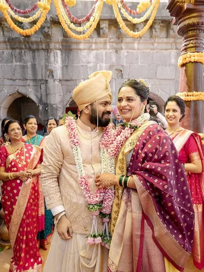 The couple shares a happy moment during their temple wedding ceremony, surrounded by family. This image captures the community aspect of a wedding, with everyone sharing in the joy.