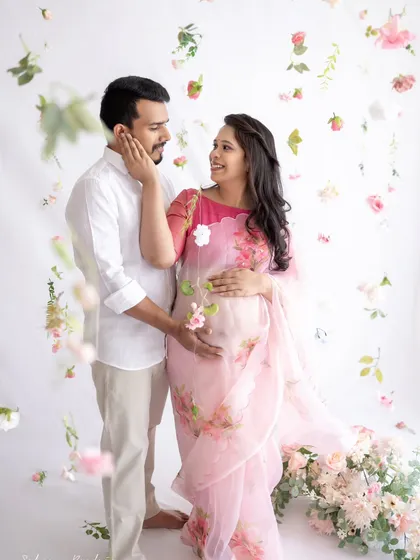 So light, so airy, so beautiful. This couple's portrait, with the mom-to-be in a delicate floral organza saree, feels like a dream. The floating flowers add a touch of magic to this tender moment.