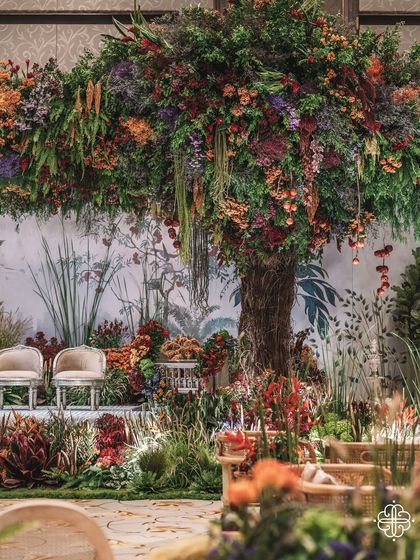 The main stage of the 'Orchard of Life' naming ceremony, with two chairs for the parents set between the magnificent floral trees.